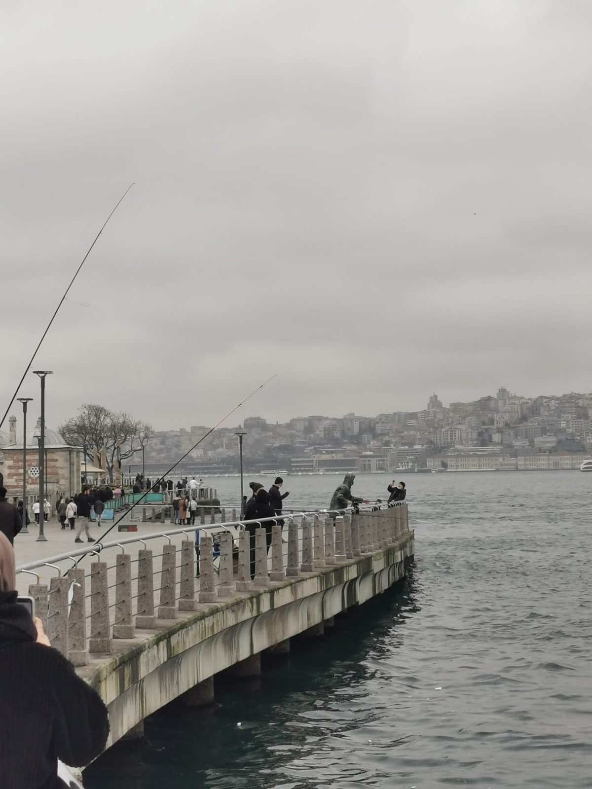 Angler am Ufer, im Hintergrund die Stadt