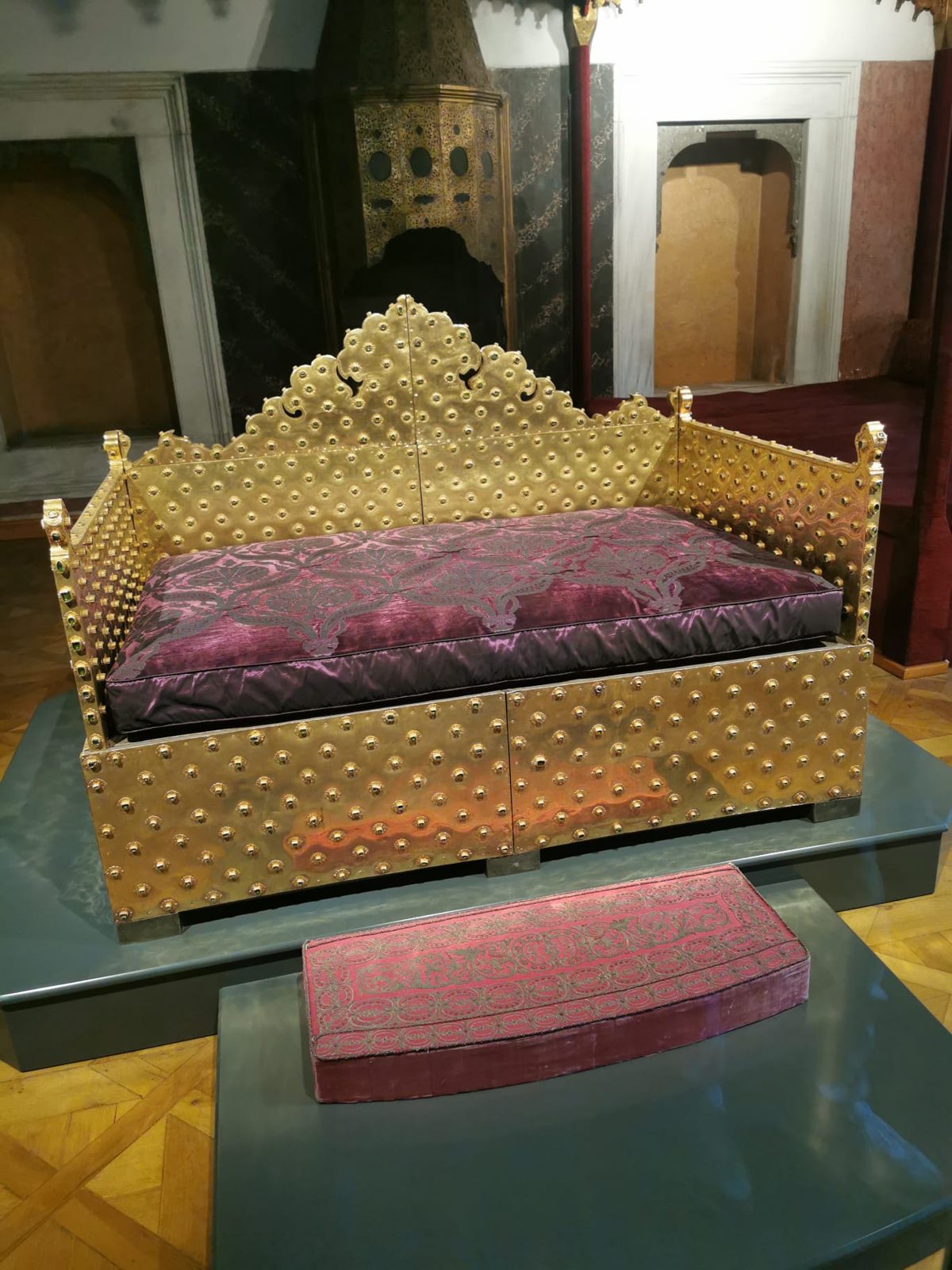 Ein goldener Sultanssitz mit roten Kissen